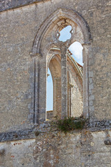 Fototapeta na wymiar Empty gothic windows in the eroded wall of old ruined Cistercian abbey on the island of Ile de Re, France