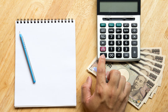 Business man calculate with calculator, and have book, japanese yen banknote on wooden background