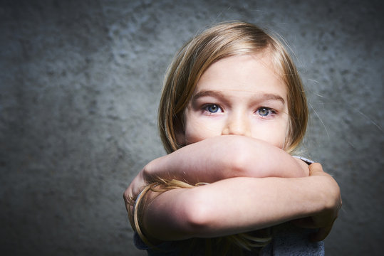 Abused child, Concept Stop violence against children. Portrait of sad and lonely girl with gray grunge wall background.