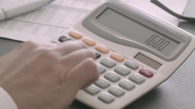 Close up of a businessman using a calculator at the office