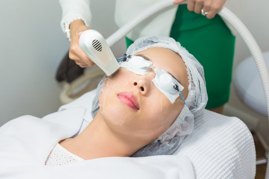 Close-up of Beautician Giving Laser Epilation Treatment To Young Woman Face.