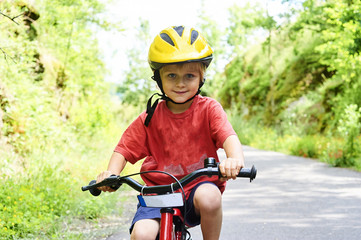 Young boy riding bicycle on a summer day at asphalt road. Bicycle path