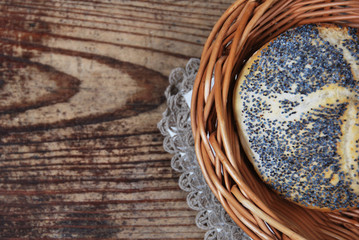 Obraz na płótnie Canvas Bread with poppy seeds in a wicker basket on a wooden table