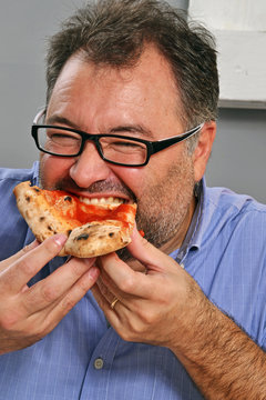 Hombre gordo comiendo un tri&aacute;ngulo de pizza
