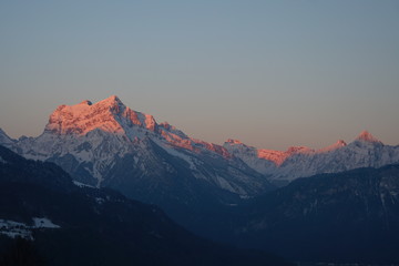 Fototapeta na wymiar Alpenglühen - Morgensonne taucht Berggipfel in rosa Licht