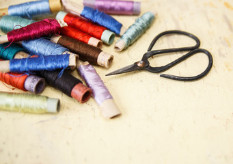 Scissors with silk threads for embroidering on vintage background 