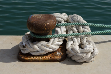 Fototapeta na wymiar Noray con cuerdas en puerto pesquero.
