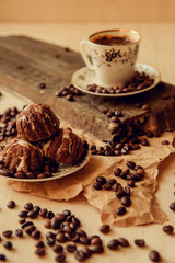 Sweet cake with a cherry and coffee beans on background of cup of coffee and warm knitted scarf. Tasty food background. Cozy winter breakfast. Good morning.