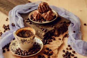 Sweet cake with a cherry and coffee beans on background of cup of coffee and warm knitted scarf. Tasty food background. Cozy winter breakfast. Good morning.