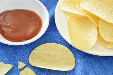 crispy and salt potato chips on dish dipping with ketchup
