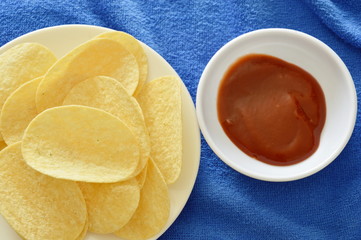 crispy and salt potato chips on dish dipping with ketchup