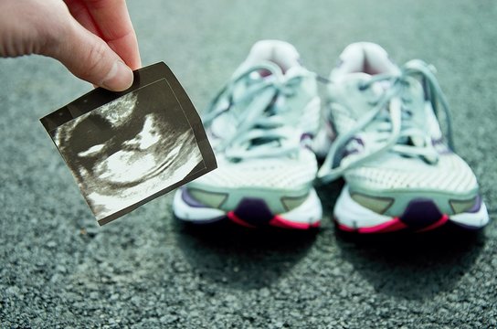 Running in pregnancy. Ultrasound image of the unborn child with running shoes and road in the background.