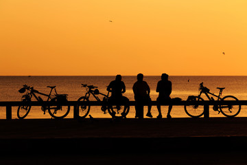 Fototapeta na wymiar Silhouette man and bike relaxing with sun flare over the beach