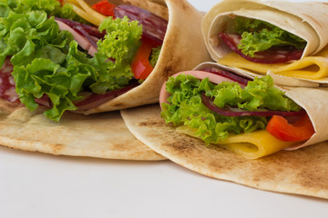 Roll tortilla with herbs, cheese and meat on a white background.