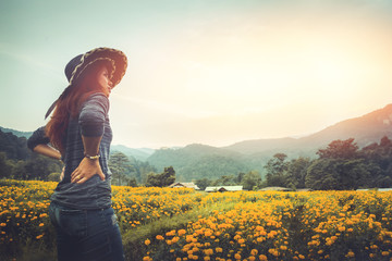 Fototapeta premium The woman stands on a field of yellow flowers. Sunset atmosphere