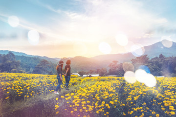 Fototapeta premium Couple of men and women walking in a field of yellow flowers. Evening sun