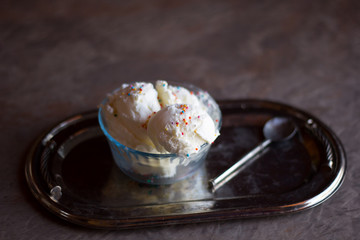 ice cream with candy sprinkles in a vintage saucer on a silver tray