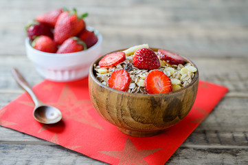 muesli with strawberry pieces in a wooden bowl