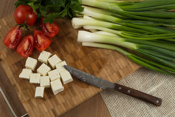 organic cheese cubes and tomatoes on wooden table top view