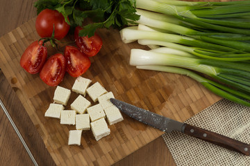 organic cheese cubes and tomatoes on wooden table top view