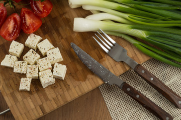 organic cheese cubes and tomatoes on wooden table top view