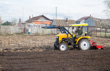 small farm tractor plowing the soil for planting