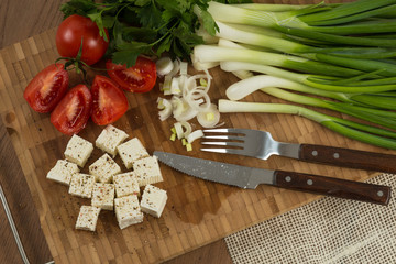 organic cheese cubes and tomatoes on wooden table top view