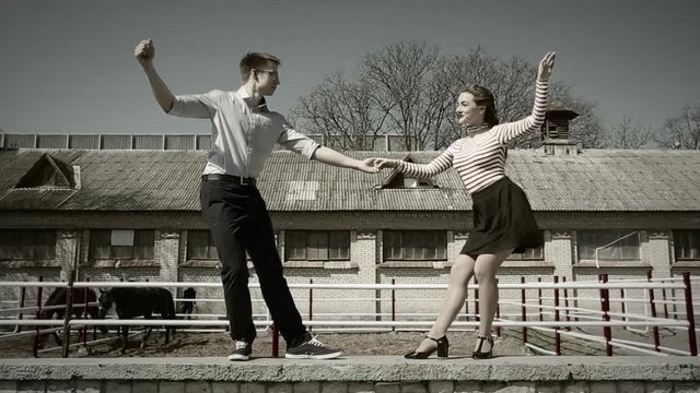 young couple dancing swing outside, the girl's skirt is flying in the wind; looping cinemagraph