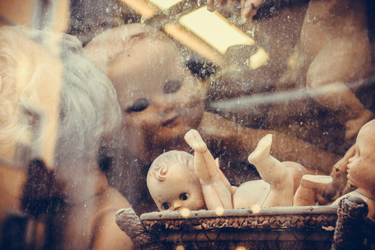Creepy broken dolls looking out through the dirty dusty window.