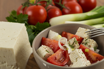 tomatoes and cheese salad with vegetables on wooden background