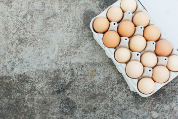 A paper tray with chicken eggs lies on a concrete table. Open space for your text, daylight.