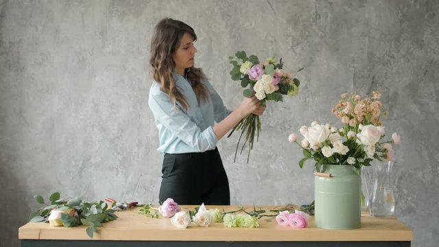 people, business, sale and floristry concept - happy smiling florist woman making bunch at flower shop, bouquet with peone and roses