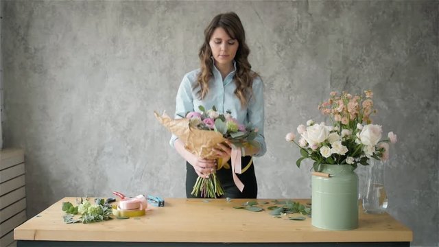 Portrait of happy female florist with bouquet roses and peone looking at camera