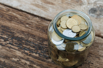 Ukrainian coins in a jar on a wooden background