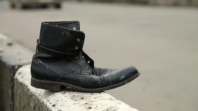 Boot near the highway, traffic violation and road accident. Old black shoe near the road. Jaywalking, do not run across road