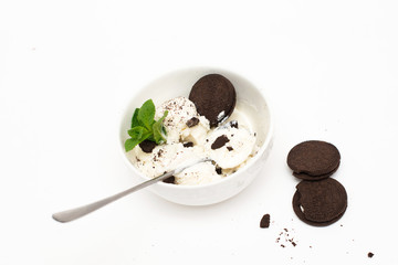 Homemade vanilla ice cream in a white ceramic bowl with chocolate chip cookies on a white background.