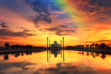 Beautiful sunset over the mosque with rainbow on cloud and sky
