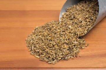 Freekeh in grain scoop in wood background