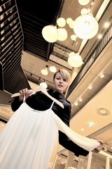 Junge, blonde Frau beim Shopping in einem Modehaus, zeigt ein Oberteil