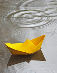 yellow paper boat in a puddle