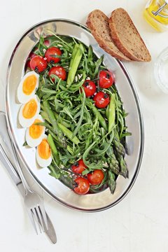 
    Asparagus salad with arugula, cherry tomatoes and eggs. Overhead view. 