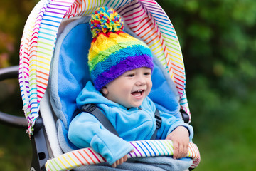 Baby boy in stroller in autumn park