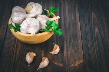 Garlic cloves and garlic bulb in a wooden bowl.