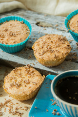 Chocolate muffin with soft cream and fresh blueberry powdered with sugar, cup of coffee, rustic background