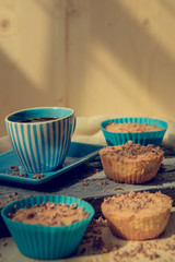Chocolate muffin with soft cream and fresh blueberry powdered with sugar, cup of coffee, rustic background