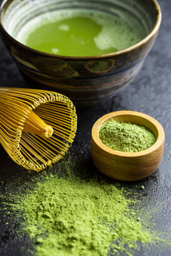 Green matcha tea powder with bamboo whisk , spoon and bowl.