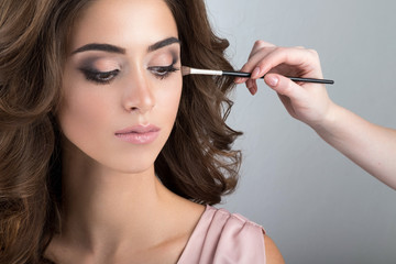 Close-up portrait of brunette while applying makeup