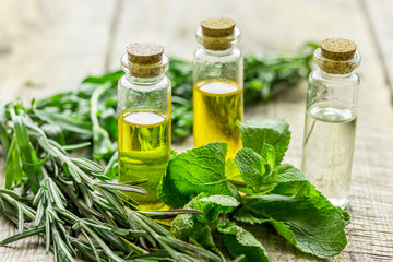 organic oil in bottle with rosemary and mint on light table background