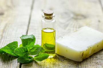 cosmetic oil in bottle and soap with herbs on light table background