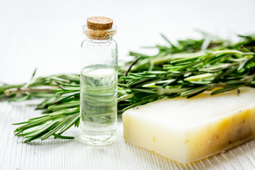 cosmetic oil in bottle with herbs on light table background